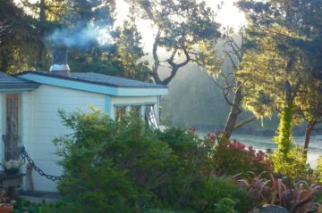 Cove room with smoke coming out the chimney - with view of sea, trees and flowering garden