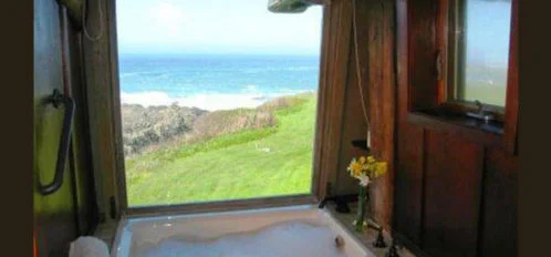 Soaking tub with a view of the cliffside and ocean